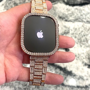 Puede incluir: Un Apple Watch de oro rosa con una banda y un bisel engastados con diamantes. La esfera del reloj es negra y presenta el logotipo de Apple.