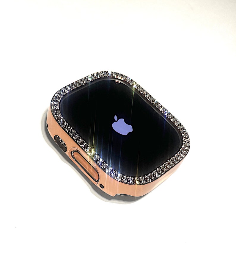 Puede incluir: Un Apple Watch de oro rosa con una caja transparente adornada con un borde brillante de cristales que parecen diamantes.