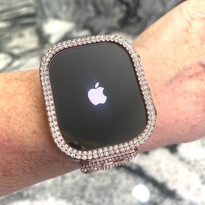 Puede incluir: Un Apple Watch de oro rosa con un bisel y una banda transparentes y brillantes, que parecen diamantes.