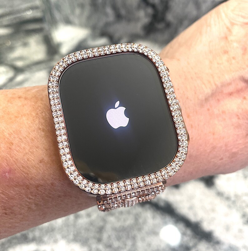 Puede incluir: Un Apple Watch de oro rosa con un bisel y una banda transparentes y brillantes, que parecen diamantes.