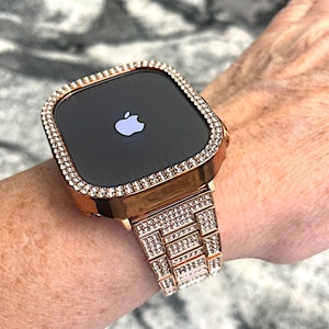 Puede incluir: Un Apple Watch de oro rosa con una banda y un bisel engastados con diamantes. La esfera del reloj es negra y presenta el logotipo de Apple.