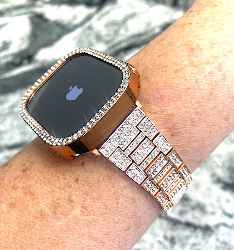 Puede incluir: Un Apple Watch de oro rosa con una banda y una caja engastadas con diamantes. La esfera del reloj es negra y muestra el logotipo de Apple.