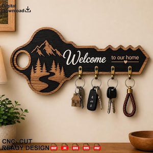 May include: A wall-mounted key holder shaped like a large key with a black and wood-grain finish. It features a mountain and forest landscape, the text "Welcome to our home" with a heart icon, and four brass hooks holding various metal keys.