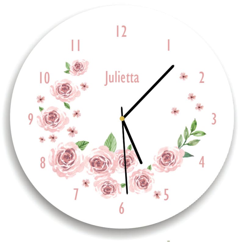 May include: White round clock with black hands and pink floral design. The clock face has black Roman numeral hour markers and the name "Julietta" printed in black.