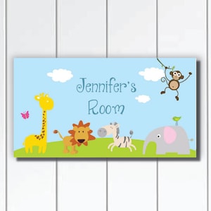 以下が含まれることがあります： 青い緑のドアサインに、青い文字で「Jennifer's Room」と書かれています。サインには、黄色のキリン、茶色のライオン、シマウマ、ピンクの耳をした灰色のゾウが描かれています。サルがつるからぶら下がり、緑の鳥がゾウの背中に乗っています。