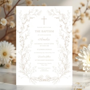 以下が含まれることがあります： 金色の花のアクセントと上部に十字架が付いた白い洗礼の招待状。「私たちの娘アメリアの洗礼」というテキストとイベントの詳細。招待状は繊細な花の要素に囲まれています。