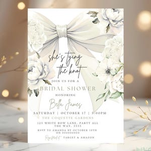 May include: Bridal shower invitation featuring a large white bow and floral accents. The invitation includes the text "she's tying the knot" and details for the event, including the date, time, and location.