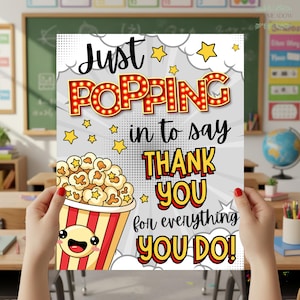 Può includere: Un poster con la scritta "Just POPPING in to say THANK YOU for everything YOU DO!" in un font giocoso. Il poster presenta un secchio di popcorn con una faccia sorridente e accenti a stella, perfetto per un regalo di ringraziamento.