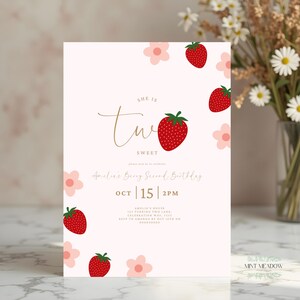 Op de afbeelding: Een lichtroze verjaardagsuitnodiging met aardbeien- en bloemillustraties. De tekst luidt "She is Two Sweet" en "Amelia's Berry Second Birthday" met datum en tijd. De uitnodiging is versierd met rode aardbeien en roze bloemen.