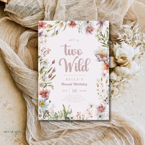 May include: A floral-themed birthday invitation with the text "She is Two Wild" in a soft pink hue. The invitation includes details for Bella's second birthday, surrounded by watercolor flowers in pink, white, and purple. The design is set against a neutral background.