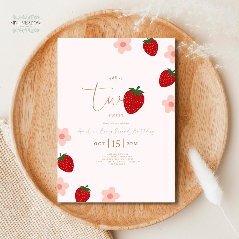Op de afbeelding: Een lichtroze verjaardagsuitnodiging met een aardbeienthema. De uitnodiging bevat de tekst "She is Two Sweet" in gouden script, samen met rode aardbeien en roze bloemen. De uitnodiging is voor 15 oktober om 14.00 uur.