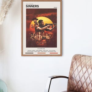 Puede incluir: Un póster enmarcado de la película "Sinners" con una escena dramática y el texto "Starring". El póster tiene una paleta de colores cálidos con un fondo similar al sol. El póster está en un marco de madera.