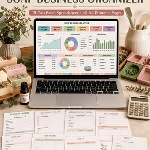 May include: A digital soap business organizer featuring a laptop displaying a dashboard with charts and financial data, surrounded by printed planner pages, a calculator, a pen, soap bars, and a bottle of lavender essential oil on a table.