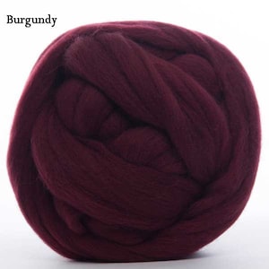 Puede incluir: Una bola de lana merina de color burdeos. El texto "Burgundy" est&aacute; en la esquina superior izquierda. La lana es gruesa y parece suave, con una forma circular y bien enrollada. El color es un tono rojo intenso con un toque de p&uacute;rpura.