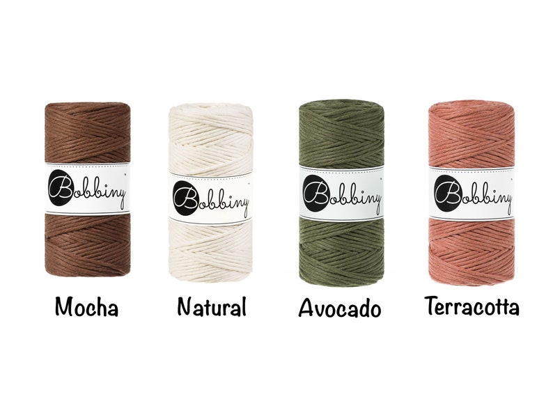 K&ouml;nnte beinhalten: Vier Spulen Bobbiny Makramee-Kordel in den Farben Mokka, Natur, Avocado und Terrakotta. Jede Spule ist mit dem Bobbiny-Logo versehen. Die Farben werden vor einem wei&szlig;en Hintergrund angezeigt, mit den Farbbezeichnungen unter jeder Spule.