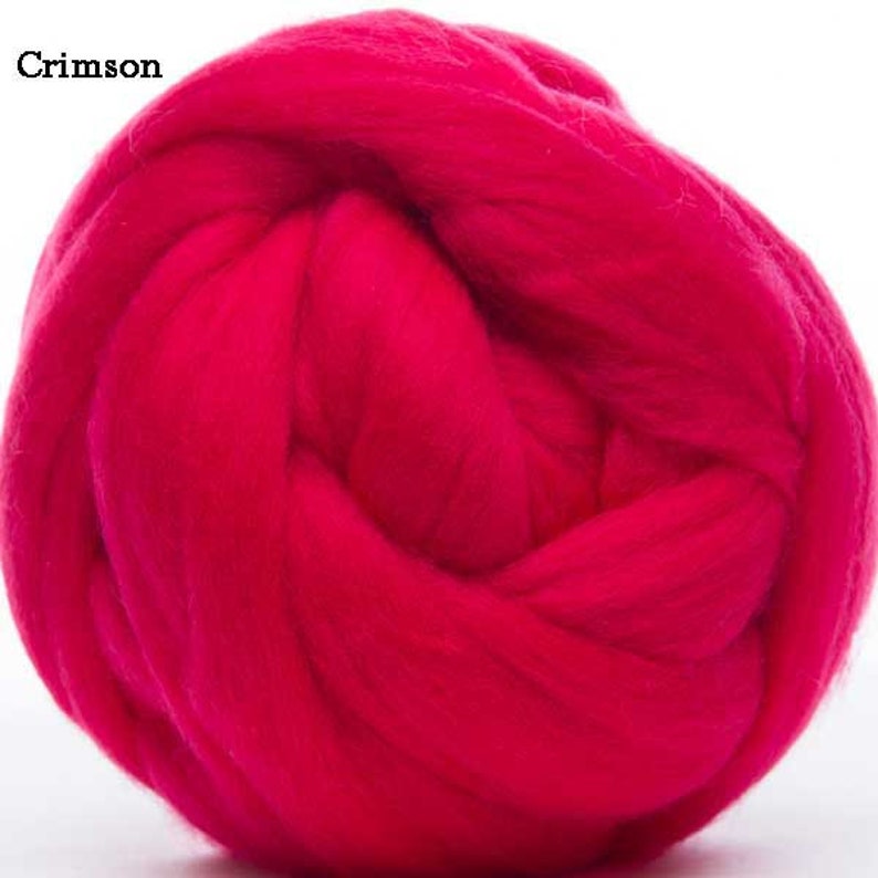 Puede incluir: Primer plano de una gran bola de lana de color carmes&iacute;. El texto "Crimson" est&aacute; en la esquina superior izquierda. La lana est&aacute; densamente empaquetada y parece suave, ideal para diversas manualidades.