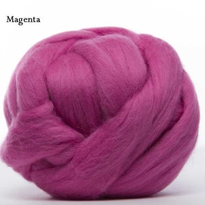 Puede incluir: Primer plano de una bola de lana de color magenta. El texto "Magenta" est&aacute; en la esquina superior izquierda. La lana est&aacute; densamente empaquetada y parece suave y esponjosa, ideal para proyectos de arte textil como fieltro con aguja o fieltro h&uacute;medo.