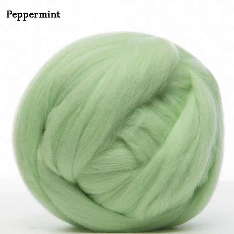 May include: A ball of light green wool roving, a type of fiber used for felting and spinning.