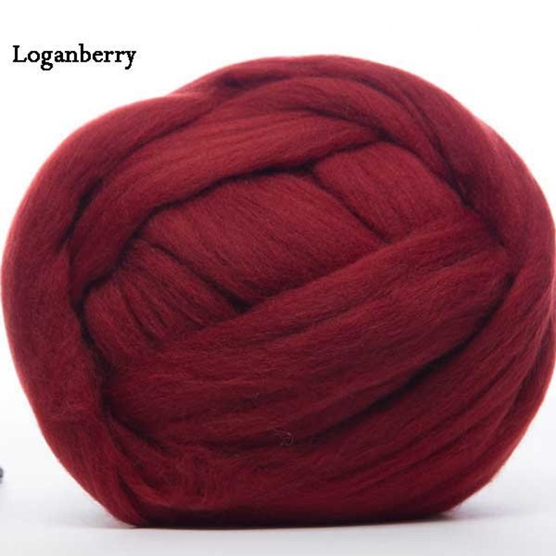 Puede incluir: Una gran bola de vell&oacute;n de lana merino color Loganberry. La lana es de un tono rojo-p&uacute;rpura profundo y rico, finamente hilada y texturizada. La imagen muestra el aspecto suave y esponjoso de la lana, ideal para varios proyectos de manualidades.