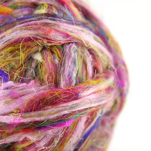 May include: A close-up of a ball of colorful yarn, featuring shades of pink, purple, blue, green, yellow, and white. The yarn is made of recycled materials and is perfect for crafting.