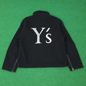 K&ouml;nnte beinhalten: Schwarze Jacke mit dem wei&szlig;en Text "Y's" auf dem R&uuml;cken. Die Jacke hat einen hohen Kragen und Rei&szlig;verschl&uuml;sse an den &Auml;rmeln. Die Jacke wird auf einer gr&uuml;nen Oberfl&auml;che pr&auml;sentiert.