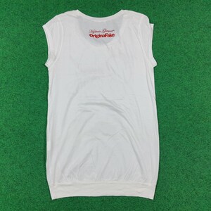Puede incluir: Una camiseta blanca sin mangas con cuello redondo y un dobladillo ancho. En la parte superior de la espalda lleva impreso en rojo el texto Hysteric Glamour y OriginaFake. La prenda presenta un dise&ntilde;o sencillo y limpio con acabado liso.