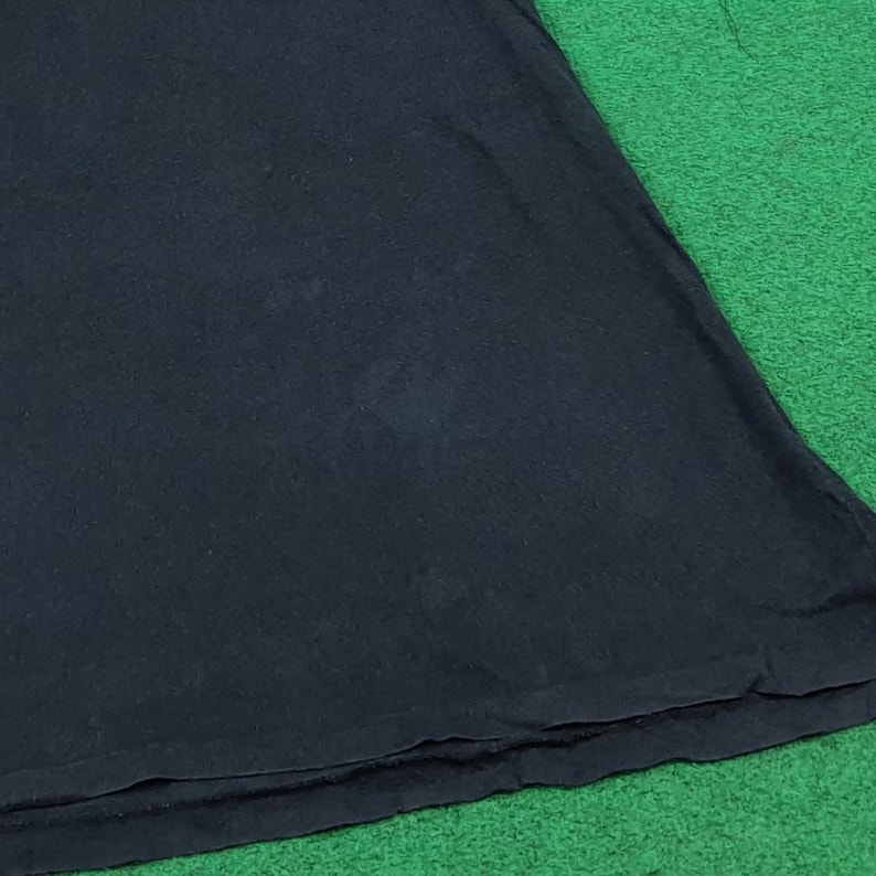 May include: A plain black t-shirt featuring a simple crew neckline and short sleeves. The fabric is a solid, dark black color with a smooth texture, showing a standard hemline at the bottom edge of the garment, presented in a clean, straightforward view.