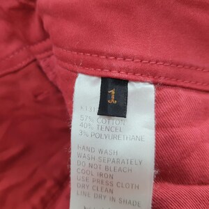 May include: Close-up of a red fabric with a tag. The tag displays the number "1" and fabric composition: 57% cotton, 40% tencel, and 3% polyurethane. Washing instructions are also visible.
