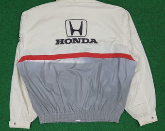 May include: Cream-colored jacket with the Honda logo and text on the back. The jacket features a red stripe across the midsection, with a gray lower panel. The jacket has a collar and a fitted waist.