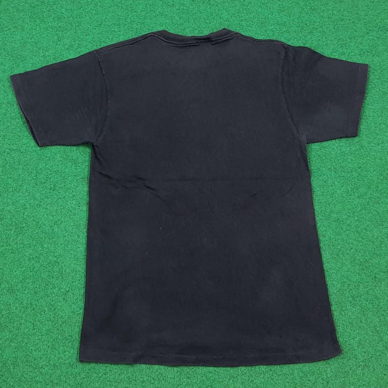 May include: A solid black short-sleeved t-shirt with a crew neckline. The garment is laid flat, displaying a plain, unadorned back side with a standard hemline at the sleeves and the bottom edge, featuring a consistent dark fabric throughout.