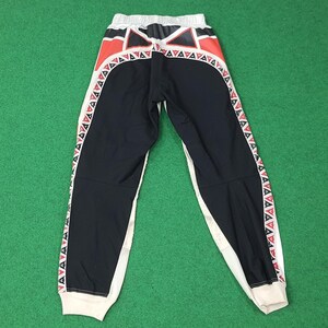 May include: Black and white athletic pants with red and white geometric designs. The pants have a white waistband and cuffs. The sides of the pants feature a repeating pattern of red and white triangles.