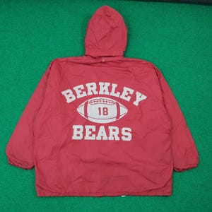 Könnte beinhalten: Rote Kapuzenjacke mit weißem Text „BERKLEY BEARS“ über einer Football-Grafik mit der Nummer „18“. Die Jacke besteht aus leichtem Material und hat eine Kapuze mit Kordelzug.