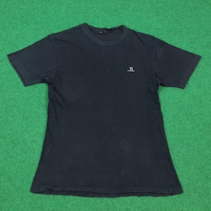 May include: A black short-sleeved t-shirt with a crew neckline. The shirt features a small white logo on the upper left chest area that reads Y's with smaller text underneath. The fabric appears to have a slightly faded, worn-in texture throughout.