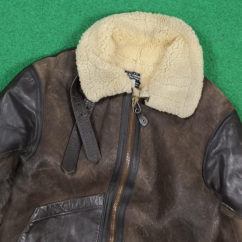 Puede incluir: Chaqueta de cuero marr&oacute;n con cuello de borrego color crema. La chaqueta tiene cremallera frontal, detalle de correa de cuero y detalles de cuero negro en hombros y mangas. Aspecto vintage y desgastado.