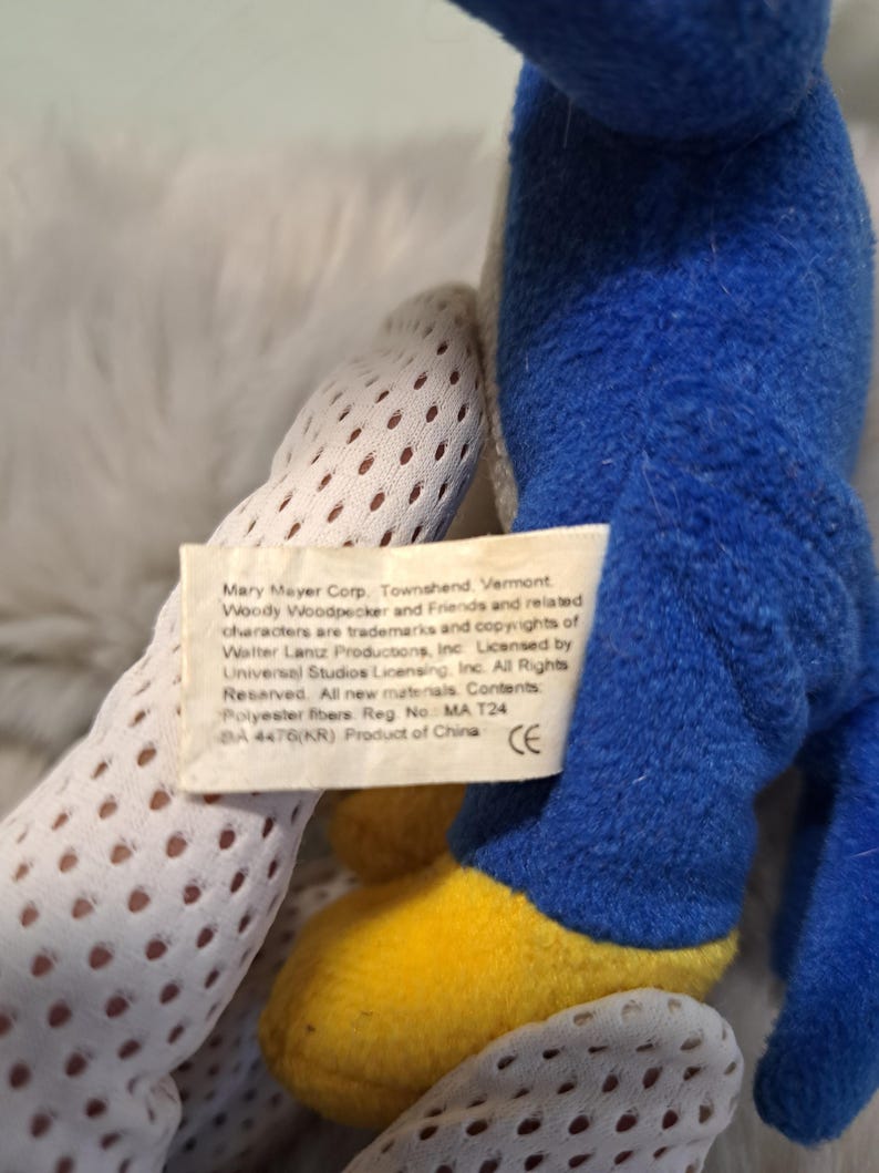 May include: A blue plush toy with yellow feet and a white fabric tag featuring the text: Mary Mayer Corp. Townshend, Vermont. Woody Woodpecker and Friends and related characters are trademarks and copyrights of Walter Lantz Productions, Inc.