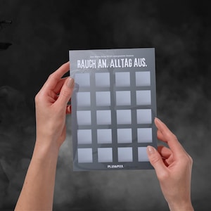 Könnte beinhalten: Eine transparente, rechteckige Karte mit einem Raster aus Quadraten, gehalten von zwei Händen. Die Karte trägt den Text "RAUCH AN. ALLTAG AUS." und "PLAN&PEEL." Der Hintergrund ist ein Grau-Schwarz-Verlauf.