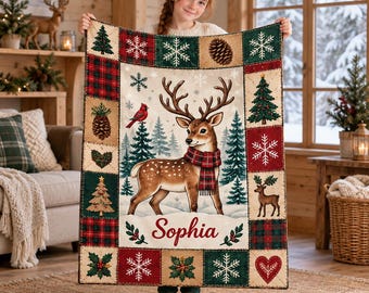 May include: A rectangular throw blanket featuring a central illustration of a deer wearing a plaid scarf, surrounded by a border of patchwork squares with Christmas trees, snowflakes, pinecones, and holly. The name Sophia is printed in red.