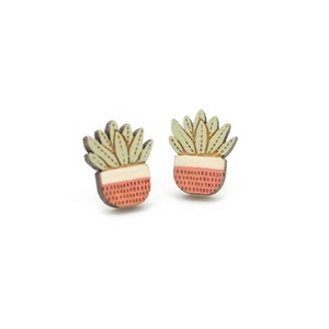 May include: A pair of wooden earrings featuring a potted succulent design. The earrings are painted in shades of green, white, and pink.
