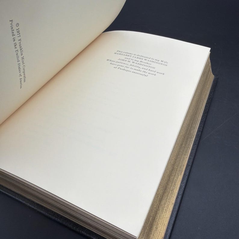Puede incluir: Un libro abierto con p&aacute;ginas color crema y bordes dorados. La p&aacute;gina izquierda tiene el texto "&copy; 1977 Franklin Mint Corporation Printed in the United States of America." La p&aacute;gina derecha tiene una dedicatoria.