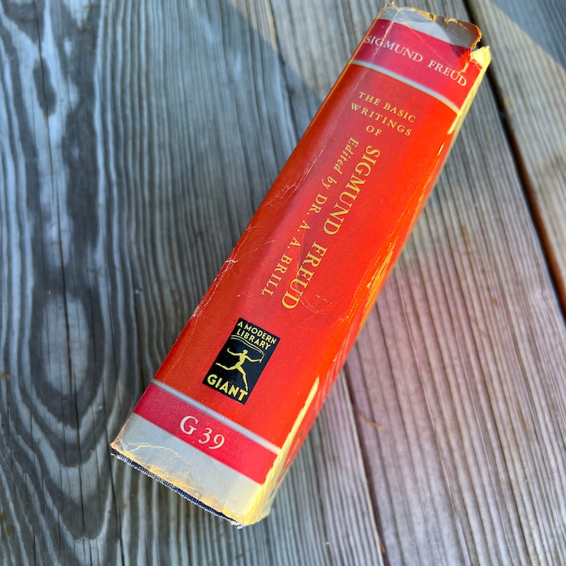 Puede incluir: Un libro rojo con el t&iacute;tulo "The Basic Writings of Sigmund Freud" de Sigmund Freud, editado por el Dr. A. A. Brill. El libro forma parte de la serie Modern Library Giant y est&aacute; etiquetado como G 39.