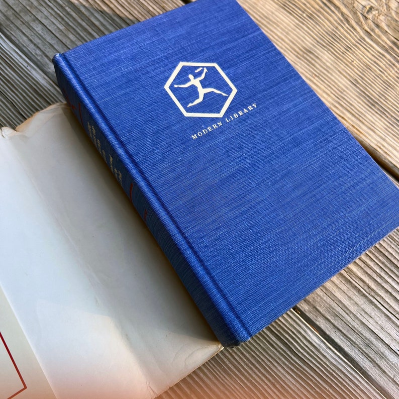 Puede incluir: Un libro de tapa dura azul con el logotipo de Modern Library en la portada. El logotipo es un hex&aacute;gono blanco con una figura de palo blanca corriendo dentro.