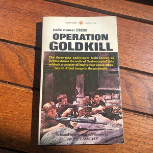 Könnte beinhalten: Ein Vintage-Taschenbuchcover mit einem Foto von drei Männern, die Waffen halten. Der Titel lautet "Operation Goldkill" und der Autor ist Bruce Cassidy. Das Buchcover ist dunkelbraun mit weißem Text.