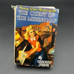 May include: Vintage hardcover book titled "Nancy Drew Mystery Stories: The Quest of the Missing Map" by Carolyn Keene. The cover features an illustration of a woman in an orange top and blue skirt, holding a map near a piano.