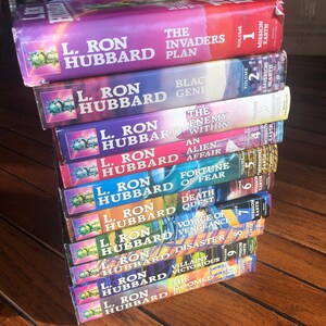 May include: A stack of ten paperback books by L. Ron Hubbard. The book titles include "The Invaders Plan", "Black Gene", "The Enemy Within", "An Alien Affair", "Fortune of Fear", "Death Quest", "Voyage of Vengeance", "Disaster", "Villainy Victorious", and "The Doomed Planet".