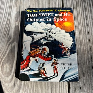 May include: A vintage book cover featuring a spaceship and astronauts in space. The title is "TOM SWIFT and His Outpost in Space" by VICTOR APPLETON II.