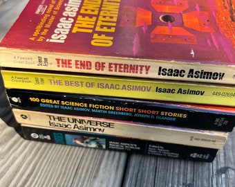 Może przedstawiać: Stosik pięciu książek science fiction w miękkiej oprawie autorstwa Isaaca Asimova. Górna książka jest czerwona z tytułem "The End of Eternity". Druga książka jest żółta z tytułem "The End of Eternity". Trzecia książka jest żółta z tytułem "The Best of Isaac Asimov". Czwarta książka jest czarna z tytułem "100 Great Science Fiction Short Short Stories". Dolna książka jest żółta z tytułem "The Universe".