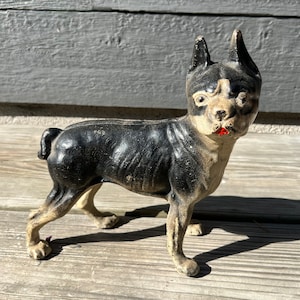 May include: Black and white cast iron Boston Terrier dog doorstop. The dog is standing on all four legs with its head tilted to the side. The dog has a black nose and white markings on its face.