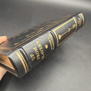 Puede incluir: Un libro de tapa dura negro con letras doradas y detalles decorativos. El libro se titula "Up From Slavery" de Booker T. Washington. El lomo muestra el t&iacute;tulo y el nombre del autor.
