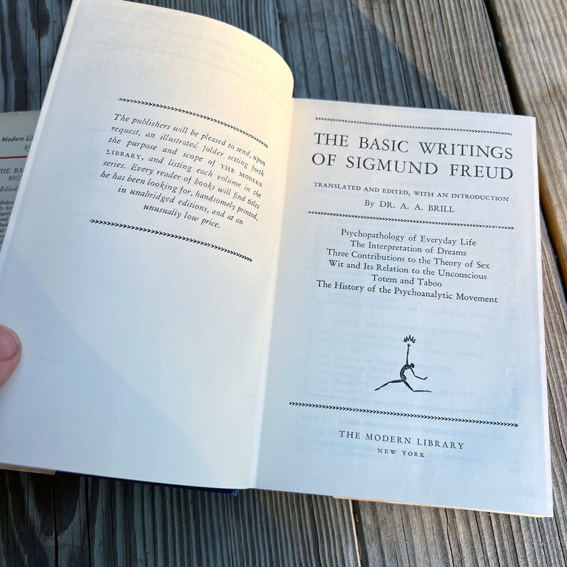 Puede incluir: Un libro blanco con texto negro en la portada. El t&iacute;tulo es "The Basic Writings of Sigmund Freud" con el subt&iacute;tulo "Traducido y editado, con una introducci&oacute;n por el Dr. A. A. Brill". El libro enumera las siguientes obras: "Psychopathology of Everyday Life", "The Interpretation of Dreams", "Three Contributions to the Theory of Sex", "Wit and Its Relation to the Unconscious", "Totem and Taboo", y "The History of the Psychoanalytic Movement". El libro es publicado por The Modern Library en Nueva York.