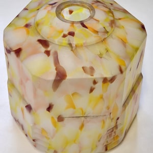 May include: An octagonal lampshade with a speckled pattern of yellow, orange, and maroon on a white background. The shade has a circular opening at the top and a stepped base. The design is geometric and decorative.